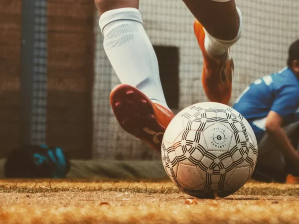 Fußballspieler im Trikot schießt einen Ball – Live-Fußball mit Sky und DAZN im Onik Döner & Pizzahaus