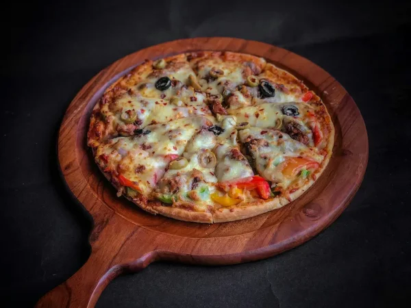 Ofenfrische Pizza auf einem runden Holzbrett – Pizzatage im Onik Döner & Pizzahaus